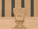 a glass vase sitting on a table with a striped chair in the background
