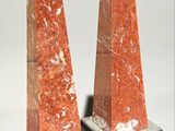 pair of red marble obelisks on black bases on a white background