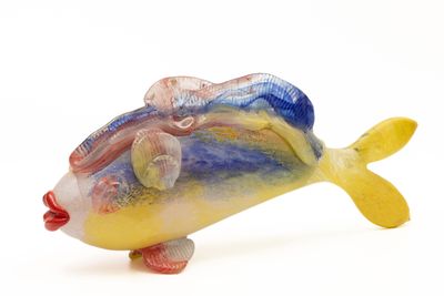 une figurine de poisson en verre posée sur une surface blanche