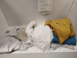a white bath tub filled with clothes and a towel
