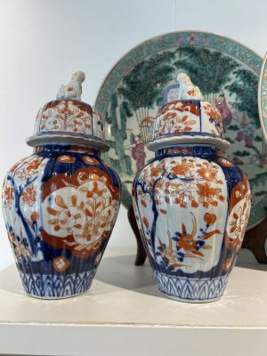 trois vases posés sur une étagère, à côté d'une assiette et d'une horloge