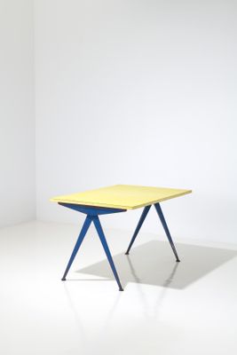 a yellow and blue table in a white room with a white wall