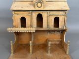 une petite maison de poupées en bois surmontée d'une horloge