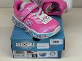des chaussures Skechers roses à semelles blanches posées sur une boîte bleue