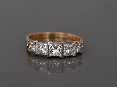a close up of a three stone diamond ring on a black surface