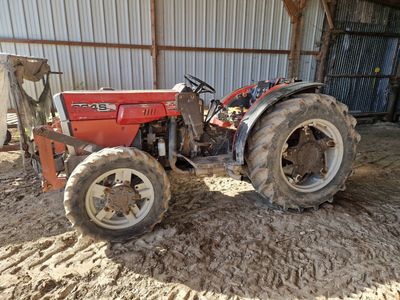 un tracteur rouge garé sur la terre battue