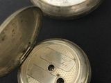 a silver pocket watch sitting on a black surface
