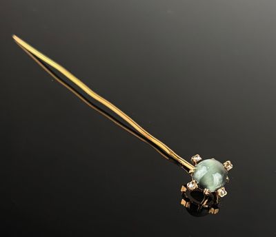 a close up of a gold stick with a green stone on it