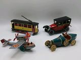quatre petites voitures et un petit avion posés sur une surface blanche