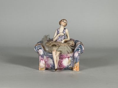 une figurine de femme assise sur une chaise