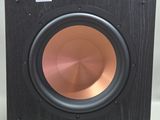 un gros plan d'un caisson de basses posé sur une surface blanche