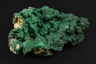 un gros plan d'un morceau de minéral vert sur une surface noire