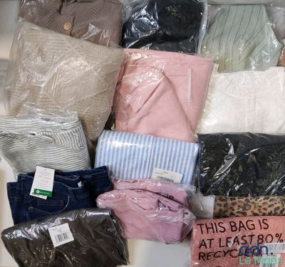de nombreux sacs de vêtements empilés les uns sur les autres sur une table