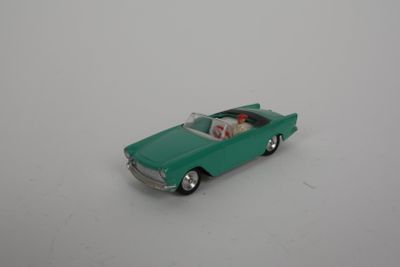 une petite voiture verte posée sur une surface blanche