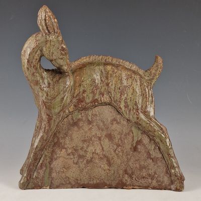sculpture représentant un cerf sur un rocher, avec un oiseau perché sur son dos