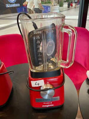 a red blender sitting on a table in front of a red chair