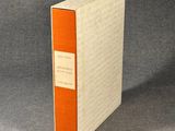 un livre orange et blanc posé sur une surface grise
