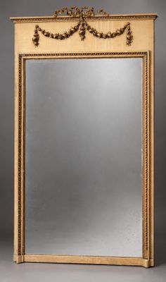 un grand miroir ancien avec un cadre doré et des ornements raffinés