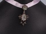 collier orné d'un ruban rose et d'un pendentif en forme de croix, porté par un mannequin