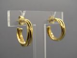 un gros plan sur une paire de boucles d'oreilles créoles en or exposées