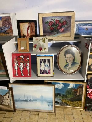 de nombreuses photos et peintures posées sur une étagère dans une pièce