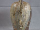 a brown vase with a handle on a gray background