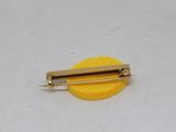 a yellow pin with a gold pin on it