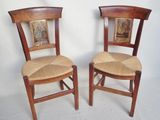 two wooden chairs with pictures on them sitting next to each other