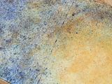 a close up of a yellow and blue tile on a wooden table