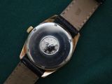 a close up of a watch on a green surface