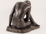 statue of a woman sitting on a rock with her back to the camera