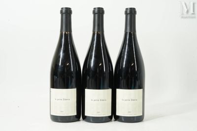trois bouteilles de vin sont alignées sur une surface blanche