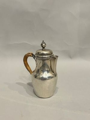 an antique silver coffee pot with a wicker handle on a white background