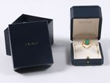 an image of a ring in a black box with a green stone