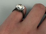 a person ' s hand holding a ring with a diamond on it