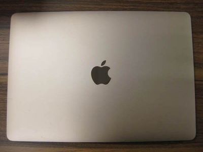 un ordinateur portable Apple posé sur une table en bois