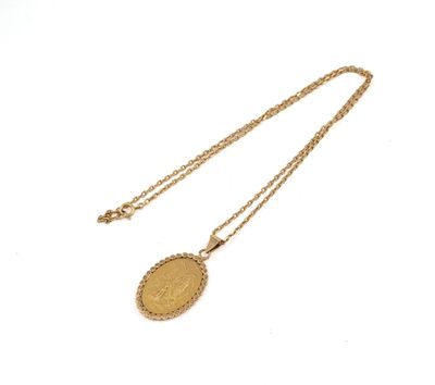 Gros plan sur un collier en or sur lequel se trouve une pièce de monnaie