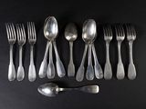 a lot of silver spoons and forks on a black table