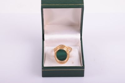 an image of a gold ring with a green stone in a box