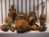 many african masks on a table with a blue and white striped background