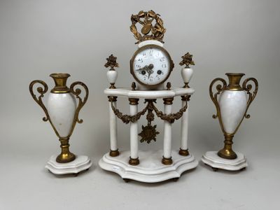 three white and gold vases and a clock on a table