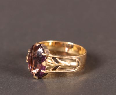 Gros plan sur une bague en or ornée d'une pierre violette.