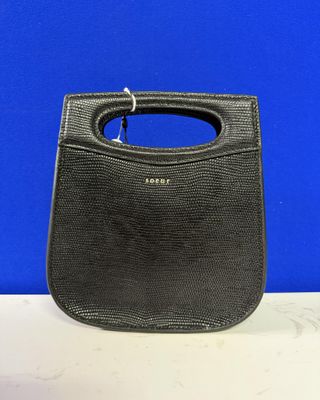 un sac à main noir muni d'une anse, posé sur une table blanche