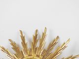 a gold sunburst hanging on the wall in the room