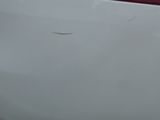 the rear end of a white car with a hole in it