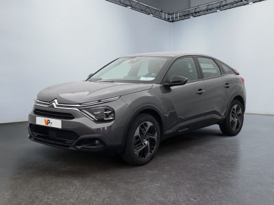 Une voiture grise est garée dans une grande pièce aux murs blancs.