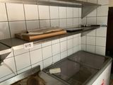 a dirty kitchen with a refrigerator and shelves in it