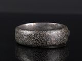 gros plan d'une bague en argent sur une surface noire