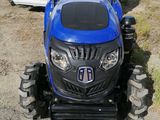 a small blue tractor parked in front of a trailer