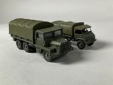 two toy army trucks sitting side by side on a white surface